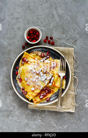 Deliziosa crepes e rabboccato con melograno e lo zucchero sulla piastra piana. laici Foto Stock