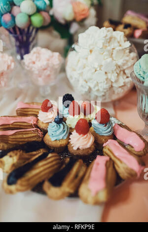 Deliziose tortine colorate e eclairs sul matrimonio candy bar Foto Stock