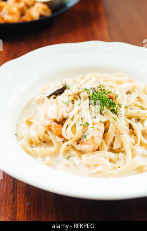 Fettucine crema bianca con salsa di gamberi e funghi nel piatto bianco - Italian food style Foto Stock