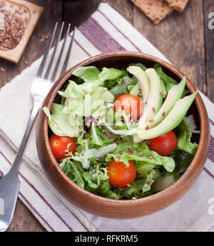 Con insalata di lattuga, pomodori, semi di lino e di avocado in una ciotola di legno. Messa a fuoco selettiva Foto Stock