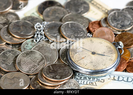 Tempo e denaro concetto Close up di un denaro e un vecchio orologio da tasca Foto Stock