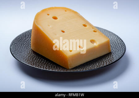 Un pezzo di tradizionali olandesi vecchio disco formaggio di latte di vacca close up su sfondo bianco Foto Stock