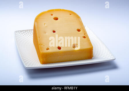 Un pezzo di tradizionali olandesi vecchio disco formaggio di latte di vacca close up su sfondo bianco Foto Stock