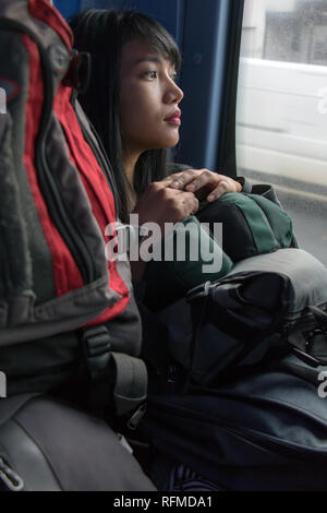 Una giovane donna fate un giro in autobus. Ragazza asiatica con molti dei sacchi in mezzi di trasporto pubblici. Un grande gruppo di bagagli bus circostante passeggero. Foto Stock