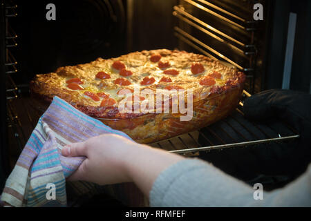 Donna mani tenendo vassoio da forno con Lasagne Vegetariane al di fuori del forno Foto Stock