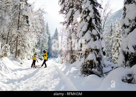 Inverno all'aperto può essere favola-maker per bambini o anche per adulti, madre e figlio permanente sulla coperta di neve trail con slittini, Slovenia, Krnica valley Foto Stock