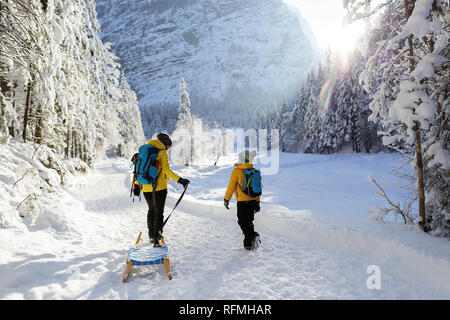 Inverno all'aperto può essere favola-maker per bambini o anche per adulti, madre e figlio permanente sulla coperta di neve trail con slittini, Slovenia, Krnica valley Foto Stock