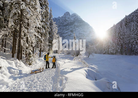 Inverno all'aperto può essere favola-maker per bambini o anche per adulti, madre e figlio permanente sulla coperta di neve trail con slittini, Slovenia, Krnica valley Foto Stock