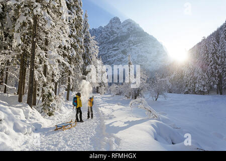 Inverno all'aperto può essere favola-maker per bambini o anche per adulti, madre e figlio permanente sulla coperta di neve trail con slittini, Slovenia, Krnica valley Foto Stock