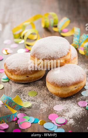 Krapfen, Berliner o ciambelle con stelle filanti e coriandoli. Coloratissimo carnevale o immagine di compleanno Foto Stock
