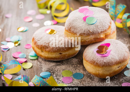 Krapfen, Berliner o ciambelle con stelle filanti e coriandoli. Coloratissimo carnevale o immagine di compleanno Foto Stock