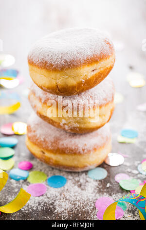Krapfen, Berliner o ciambelle con stelle filanti e coriandoli. Coloratissimo carnevale o immagine di compleanno Foto Stock