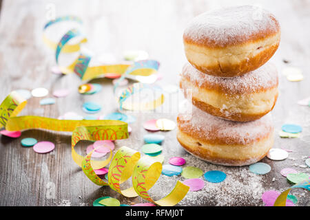 Krapfen, Berliner o ciambelle con stelle filanti e coriandoli. Coloratissimo carnevale o immagine di compleanno Foto Stock