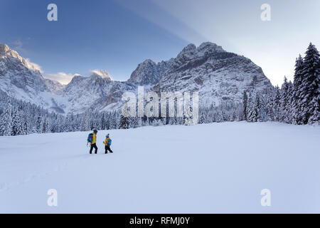 Inverno all'aperto può essere favola-maker per bambini o anche per adulti, madre e figlio permanente sulla coperta di neve valle, montagne nel retro, Europa Foto Stock