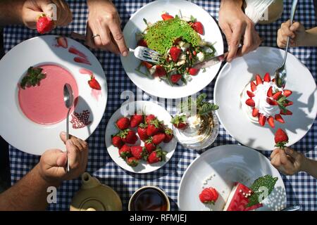 La famiglia a tavola a mangiare fragole dolci vista superiore Foto Stock