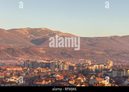 Ora d'oro vista di Pirot cityscape, e impressionante, rocciosa, vertice soleggiato sopra la città Foto Stock