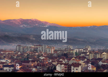 Golden sky e impressionante, rocciosa, vertice soleggiato sopra misty cityscape Foto Stock