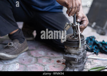 Un meccanico con cuscinetto strumento tracker consente di rimuovere una puleggia Foto Stock