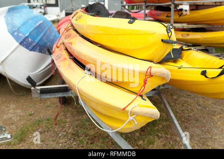 In presenza di luce solare, rosso, giallo e bianco kayak capovolto su metallo rack di stoccaggio. Canoa rifornito in Brest, Francia 28 maggio 2018. Foto Stock