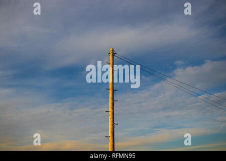 Palo del telegrafo contro un nuvoloso cielo blu in inverno Foto Stock