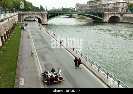 Parigi, Francia 01 giugno 2018 un compagno di giovani bevande e mangia sulle rive del Fiume Senna nel centro di Parigi. Concetto picnic in c Foto Stock