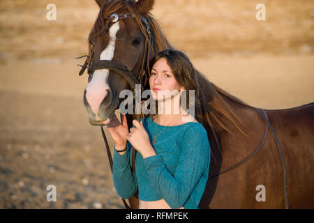 Ragazza adolescente e un cavallo in piedi accanto a ogni altra guardando nella stessa direzione (appena fuori la telecamera) nella luce calda del pomeriggio Foto Stock