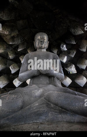 Una vista di un Buddha in uno degli stupa al tempio di Borobudur in Java, Indonesia. Foto Stock