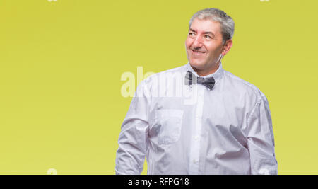 Bello il senior uomo che indossa il filtro bow tie su sfondo isolato che guarda lontano a lato con il sorriso sul volto, espressione naturale. Ridendo fiducioso. Foto Stock