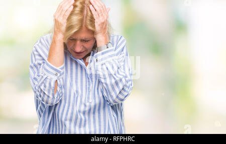 La mezza età bionda business donna su sfondo isolato che soffrono di mal di testa disperato e ha sottolineato perché il dolore e l'emicrania. Mani sulla testa. Foto Stock