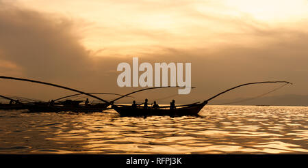 Tramonto d'oro con le tradizionali barche da pesca sul lago Kivu, Ruanda. Sagome di barche e pescatori - la luce del sole sull'acqua. Foto Stock