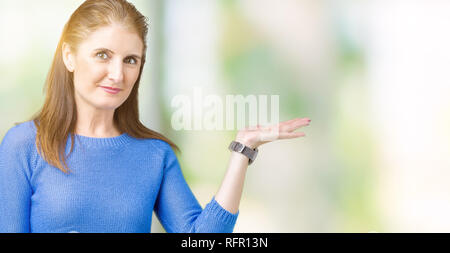 Bella la mezza età coppia donna che indossa un maglione invernale su sfondo isolato sorridente allegro presentando e dispositivo di puntamento con il palmo della mano in cerca di un Foto Stock