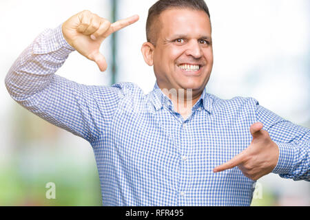 Età media arab business man over isolato sorridente sfondo rendendo il telaio con le mani e le dita con la faccia felice. La creatività e il concetto di fotografia. Foto Stock