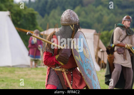 Battaglia medievale ri-enactment con gli uomini che indossano un casco spangenhelm e. catena posta aventail o camail per proteggere il collo con un mace Foto Stock