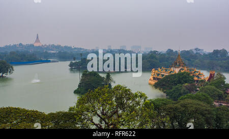 Vista del lago Kandawgyi in una piovosa serata con golden Shwedagon pagoda a distanza Foto Stock