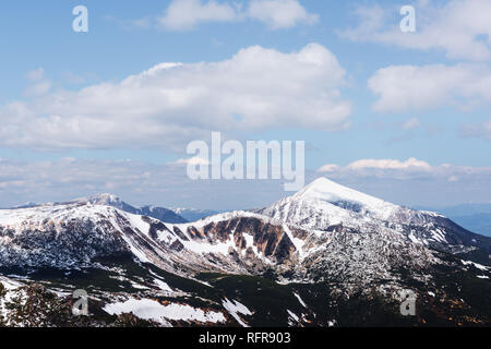 Vista delle colline pietrose con la neve e il blu del cielo. Molla di drammatica scena. Fotografia di paesaggi Foto Stock