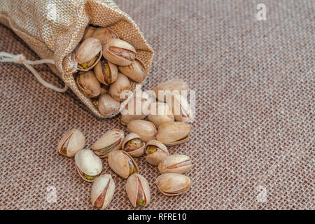 Pistacchi sacco (Pistacia vera) versato sulla superficie del sacco Foto Stock