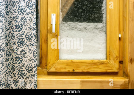 Finestra con un telaio di legno, snowbound esterno e coperto di brina, Mezza tenda chiusa. Foto Stock