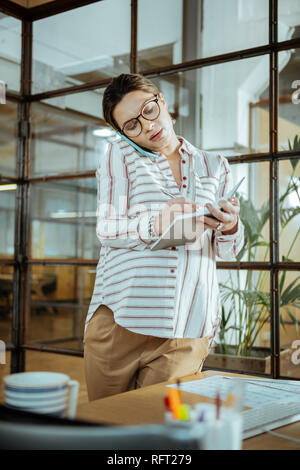 Incinta interior designer che indossa pantaloni beige parlando con il cliente Foto Stock