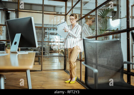 Incinta imprenditrice che indossa pantaloni beige e scarpe di colore giallo Foto Stock