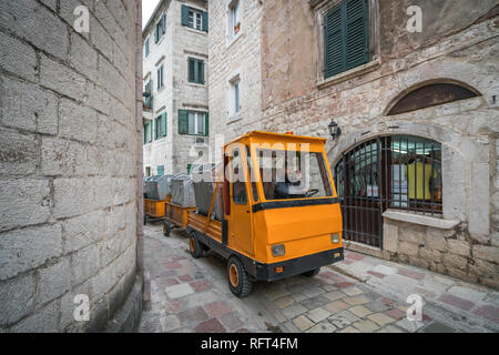 Kotor, Montenegro - Aprile 2018 : giallo auto elettrica con rimorchi a raccogliere la spazzatura da edifici residenziali di Cattaro Città Vecchia Foto Stock