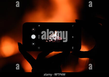 Una donna è visto scattare una foto vicino a un falò durante 'Las Luminarias' tradizione nel piccolo villaggio di Rebollo de Duero, a nord della Spagna. La tradizione, che è centinaia di anni, è destinato a purificare e a proteggere, con un grande falò, gli animali e le persone nel prossimo anno. Centinaia di villaggi e città della Spagna hanno celebrato questa tradizione durante secoli, ma oggi la celebrazione è stata persa in molti di essi. Foto Stock