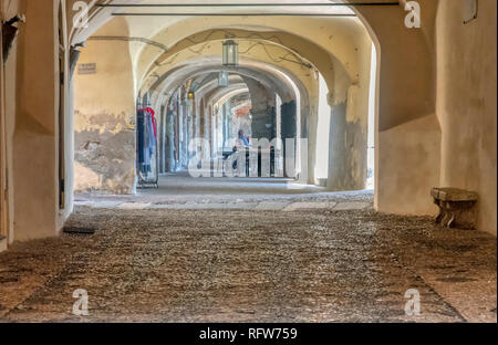 Caratteristici ciottoli arcuata passerella rientranti nella distanza sotto le storiche costruzioni medievali in Noli, Liguria, Italia Foto Stock