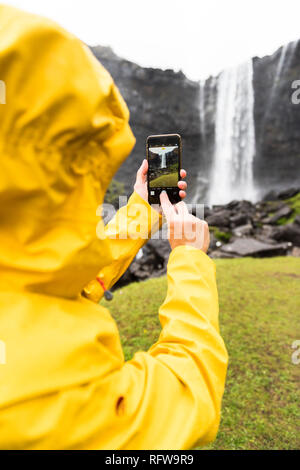 Tourist scatta le foto con lo smartphone, Fossa cascata, Streymoy isola, isole Faerøer, Danimarca, Europa Foto Stock