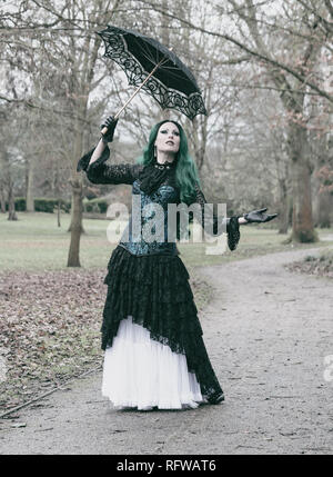 Gotica vittoriana lady con corsetto blu e verde di capelli. Camminare in un parco. L'inverno. Foto Stock