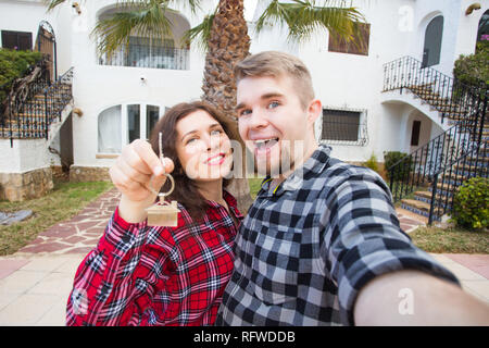 Immobiliare di proprietà e di concetto - coppia felice tenendo premuto i tasti per nuova casa e casa miniatura Foto Stock