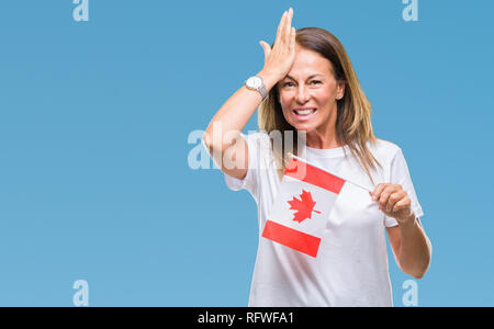 Medioevo donna ispanica holding bandiera del Canada su sfondo isolato ha sottolineato con la mano sulla testa, sconvolto con vergogna e la sorpresa di fronte, e arrabbiato Foto Stock