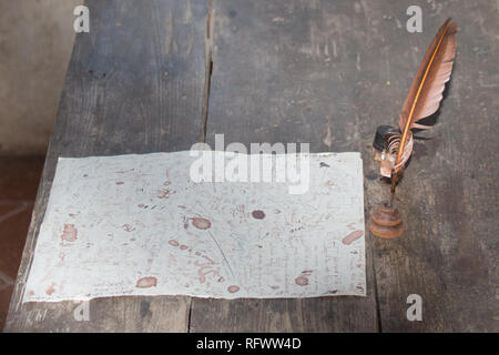 La vista di un cappello di piume e incompiuta lettera su una scrivania in legno. Foto Stock