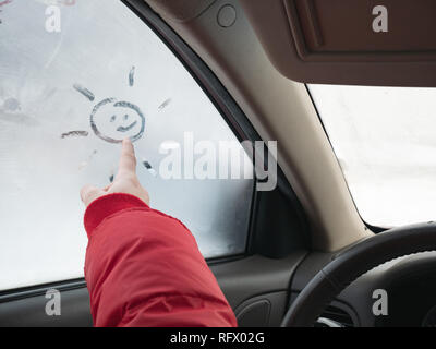 Ragazze disegnare a mano sun su congelato la finestra Auto in inverno Foto Stock