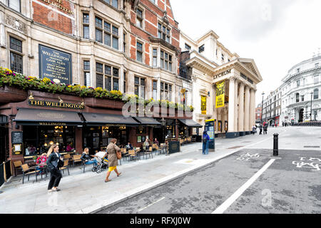 London, Regno Unito - 12 Settembre 2018: la gente camminare il pendolarismo sulla strada per strada con il Wellington pub ristorante segno e marciapiede in The Strand in grotta Foto Stock