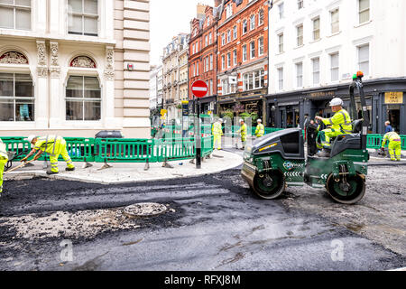 London, Regno Unito - 12 Settembre 2018: lavoratori edili con uniformi giallo edificio lavoro road con il nero catrame e asfalto Bitume nel sito della città e r Foto Stock